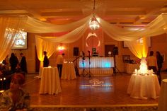 a wedding reception with white draping and yellow lights