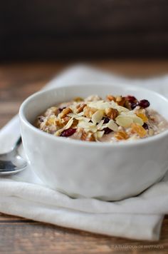 a bowl of oatmeal with nuts and cranberries sits on a napkin