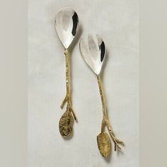 two silver spoons with gold leaves on them