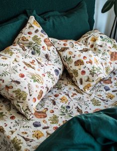 two pillows on top of a bed with green sheets and pillow cases in front of them