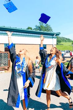 two girls in graduation gowns are throwing their caps into the air while they walk