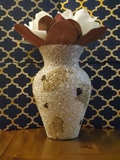 a vase with flowers in it sitting on a table next to a blue and white wall