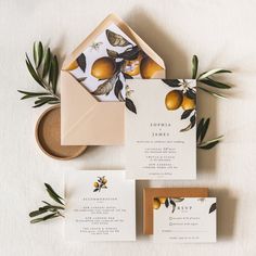 the wedding stationery is laid out with an envelope and some oranges