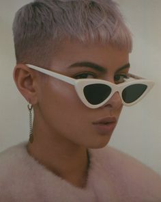 a woman with pink hair wearing white sunglasses