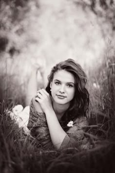 a woman laying in the grass with her hands on her chest and looking at the camera