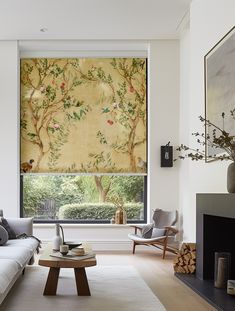 a living room with a couch, coffee table and large window covered in wallpaper