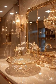 a fancy bathroom vanity with gold fixtures and chandelier in the mirror behind it