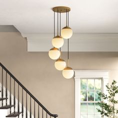 the light fixture is hanging from the ceiling above the stairs in this living room with beige walls and white trim