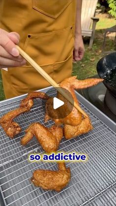 someone cooking chicken wings on a grill with a wooden stick in their hand and the words so addative