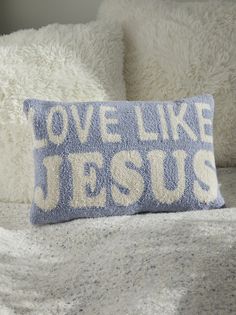 a blue and white pillow with the words love like jesus on it sitting on a bed