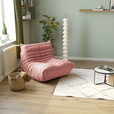 a living room with a pink chair and white rug