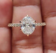 a woman's hand holding an oval diamond ring