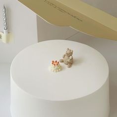 there is a small cake on the table with a teddy bear figurine next to it