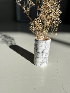 a marble vase with dried flowers in it