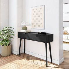 a living room with a black table and potted plant on the floor next to it