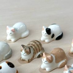 small ceramic cat figurines are arranged on a table top with white and brown cats