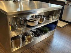 a stainless steel kitchen island with pots and pans