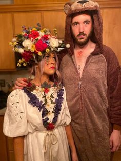 a man and woman dressed up as bears with flowers on their heads, standing next to each other