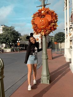 a woman standing next to a lamp post decorated with pumpkins