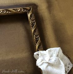 a gold frame with a white flower on it sitting on top of a brown table