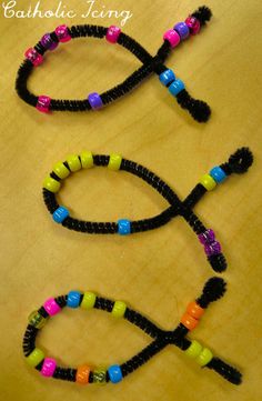 two bracelets made out of black string and colorful beads on a wooden table with the words catholic living written across them