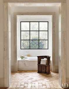 an open door leading to a bathroom with a bathtub and window in the background