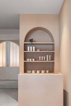 a shelf with cups and plates on it in front of a doorway that leads to another room