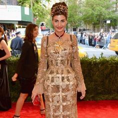 a woman in a gold dress standing on a red carpet