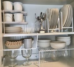 dishes and glasses are stacked on shelves in the kitchen