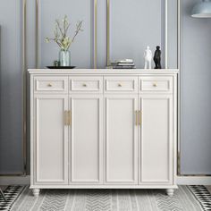 a white sideboard with gold handles and drawers in a blue living room, next to a black and white checkered rug