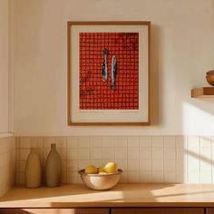 a bowl of fruit sitting on top of a counter next to a vase and painting