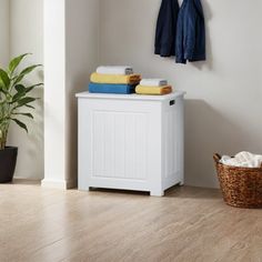 a white cabinet sitting next to a potted plant on top of a hard wood floor