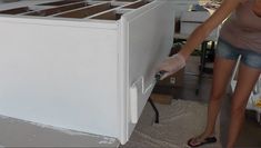 a woman standing next to a white refrigerator freezer on top of a floor covered in dirt