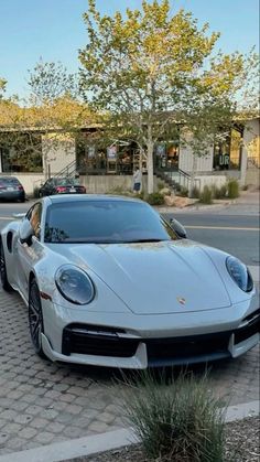 a white sports car parked on the side of the road in front of a building