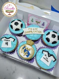 four cupcakes in a box with soccer themed frosting and decorations on them