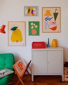 a living room with pictures on the wall and a green chair in front of it