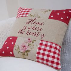 a red and white pillow that says home is where the heart is