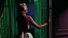 a woman standing in front of a green curtain with her hand on the door handle