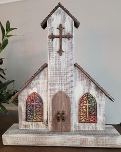 a wooden church with stained glass windows and a cross on the front door is sitting on a table