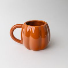 an orange coffee cup sitting on top of a white table