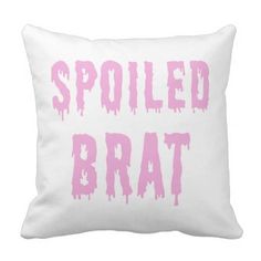 a white pillow with pink paint splattered on it that says spoiled bratt