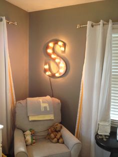 a child's room with a chair, teddy bear and light - up letter