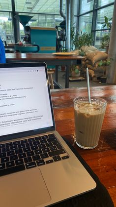 an open laptop computer sitting on top of a wooden table next to a cup of coffee