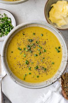 two bowls filled with soup on top of a white table next to silver spoons