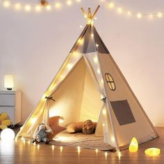 a teepee is lit up with fairy lights in the corner and on the floor