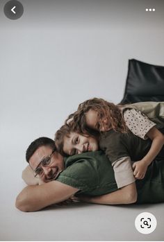 a man and two children are laying on the floor with their arms around each other