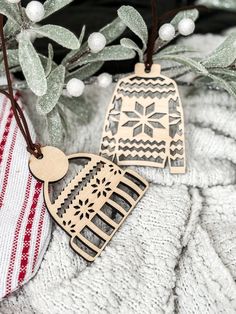 two wooden ornaments hanging from a tree branch on top of a white and red blanket