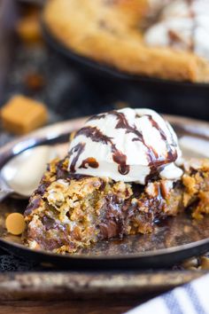 a piece of dessert on a plate with ice cream and caramel pieces in the background