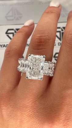 a woman's hand with an engagement ring and three stone diamond set on it