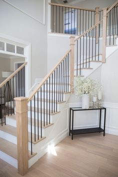 there is a vase with flowers sitting on the table next to the stairs in this house